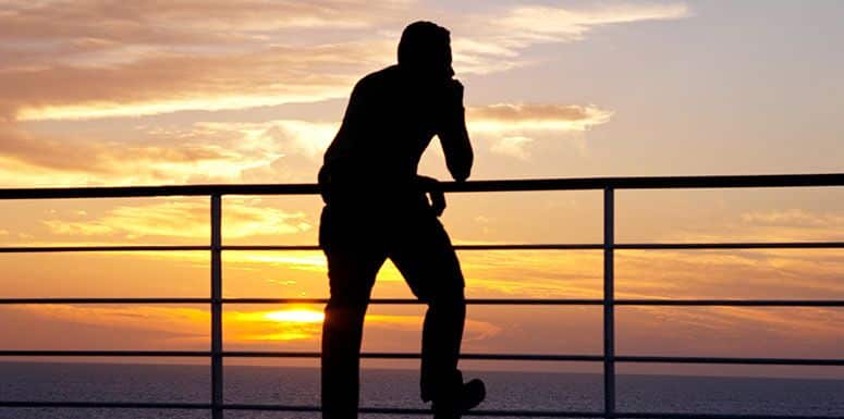 Man Looking at the Sky While Leaning on a Fence