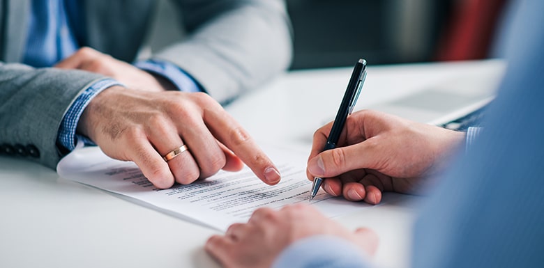 Man pointing and telling another man where to sign a document