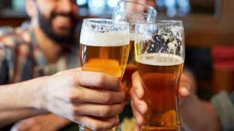 Three men holding up full glasses of beer