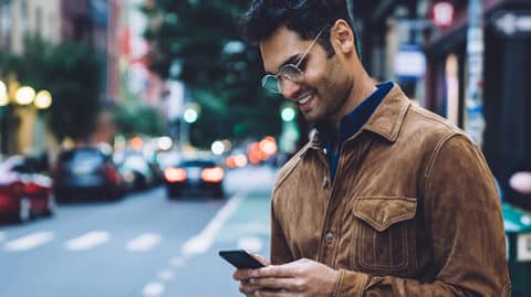 Man texting on phone before crossing street