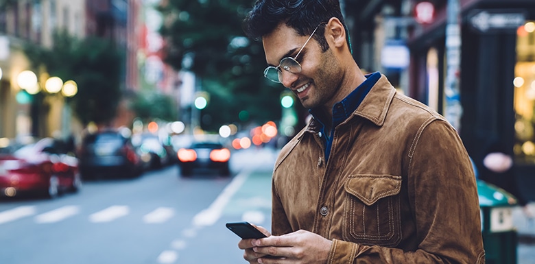 Man texting on phone before crossing street