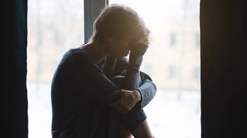 Upset man curled up in window seat