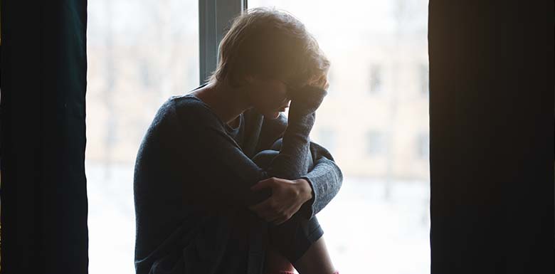 Upset man curled up in window seat