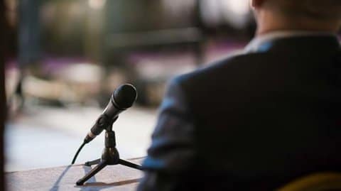 Man in suit talking into a microphone