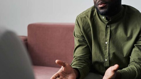 Man on sofa explaining something seriously