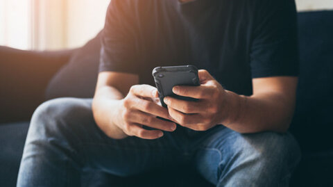 Man sitting on his couch sending a text to someone