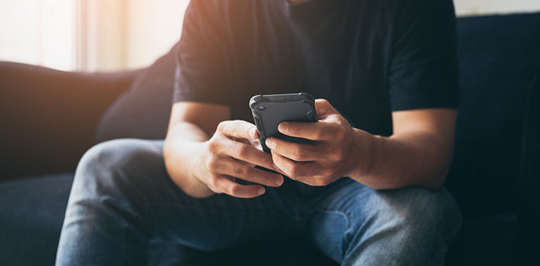 Man sitting on his couch sending a text to someone
