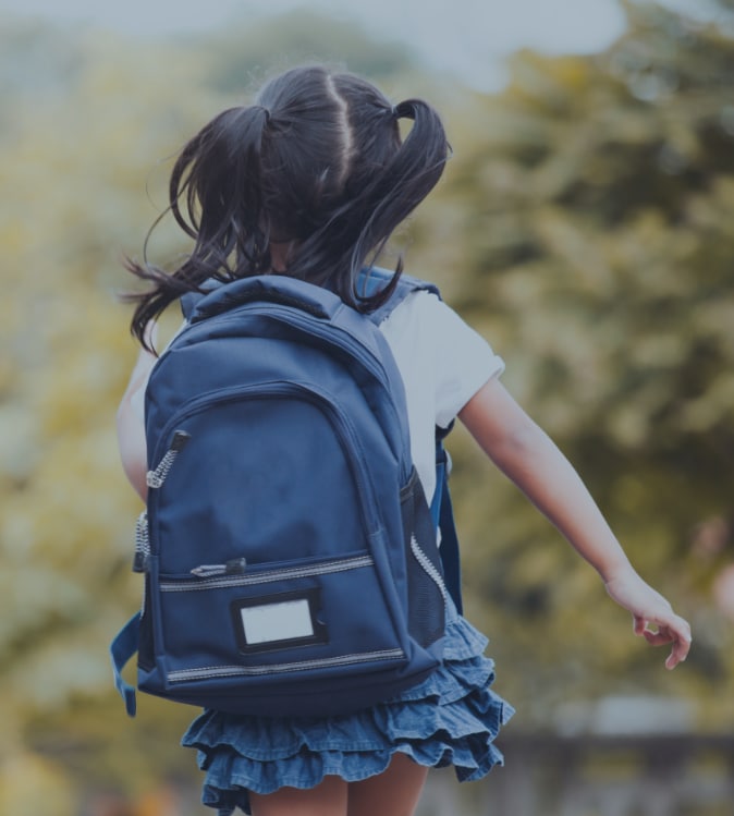 child with black hair in ponytails wearing blue backpack