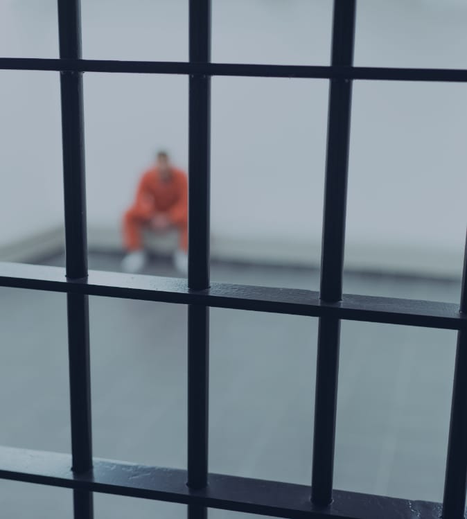 man wearing orange jumpsuit sitting in prison cell