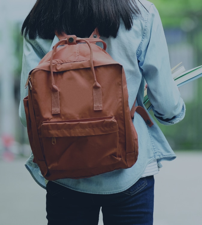 young adult female wearing backpack and holding textbooks